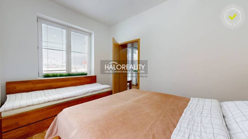 Hálószoba egy háromszobás lakásban, két ággyal és redőnyös ablakkal.