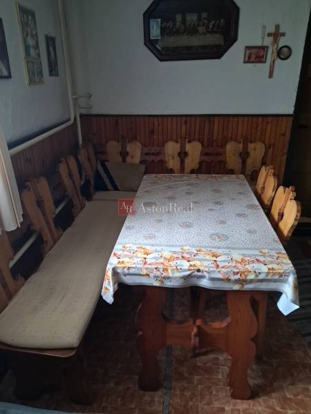 Ebédlő egy családi házban fa székekkel és asztallal, a falat képek és egy kereszt díszítik.