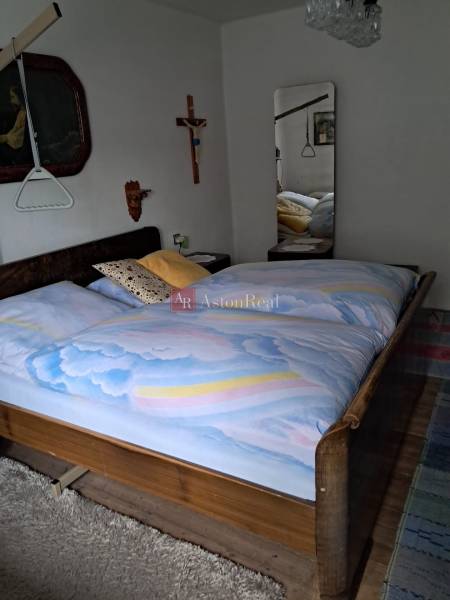 Hálószoba családi házban fa dekorációval, nagy tükörrel és fali dekorációkkal.