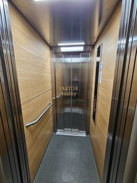 A lift belseje fa dekorációs panelekkel és rozsdamentes acél elemekkel.
