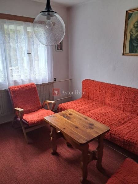 Egy szoba családi házban piros székekkel, asztallal és függönyökkel.