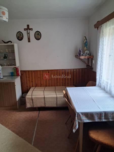 Ebédlő egy családi házban, asztallal, székekkel és vallási dekorációkkal a falon.