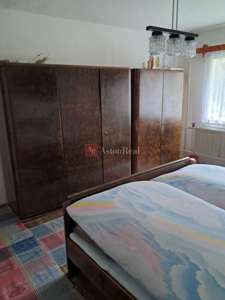 Hálószoba családi házban ággyal, szekrényekkel és színes mintás szőnyeggel.