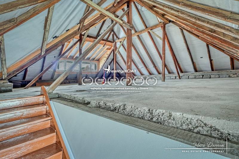 Padlás családi házban látható fa gerendákkal és lépcsővel.