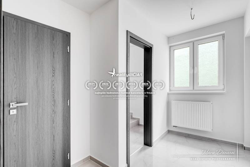 Családi ház belső tere fehér falakkal, fa dekorációjú műanyag ablakokkal és ajtókkal.