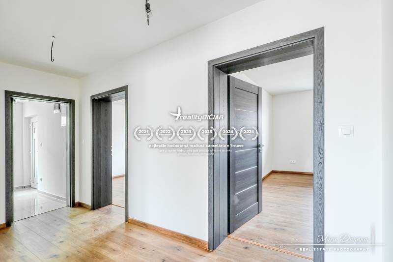 Családi ház belső tere fa dekorációjú padlóval és fehér falakkal.