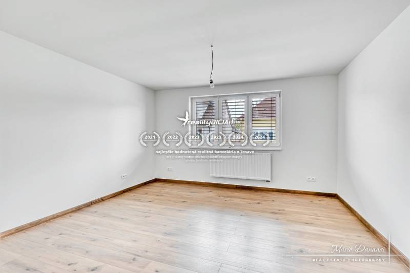 Üres szoba egy családi házban, fa dekorációjú padlóval és fehér falakkal.