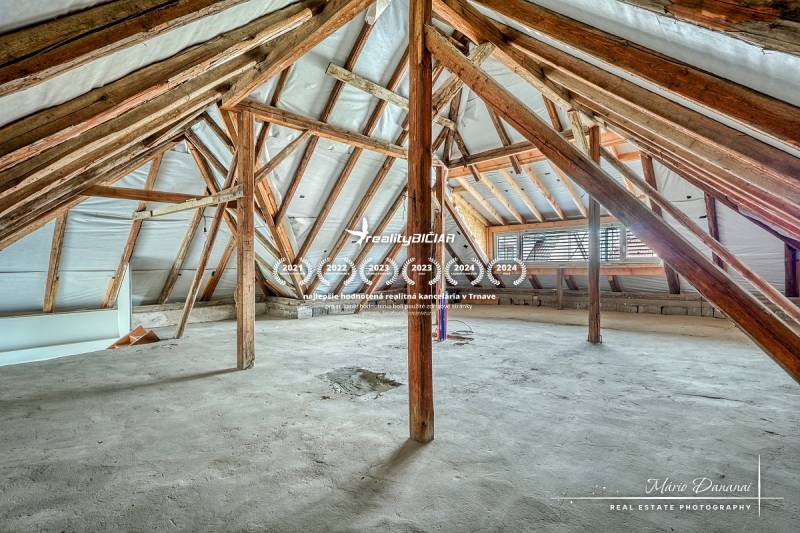 Családi ház padlása fa gerendákkal és nyers padlóval.