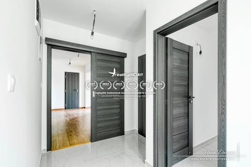 Családi ház belső tere sötét ajtókkal és fa dekorációjú padlóval.