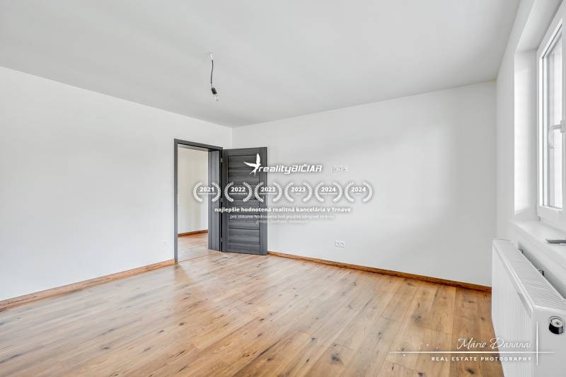 Szoba egy családi házban fehér falakkal és fa dekorációjú padlóval.