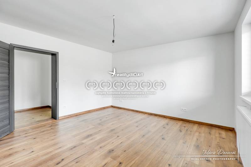 Szoba fehér falakkal és fa dekorációjú padlóval egy családi házban.