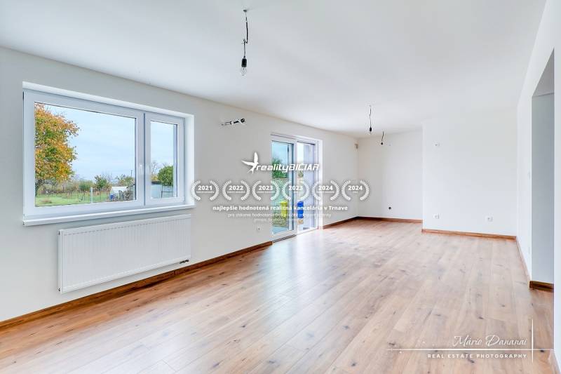 Tágas nappali családi házban, fa dekorációjú padlóval és nagy ablakokkal.