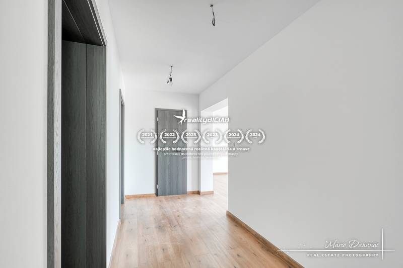 Folyosó egy családi házban, fa dekor padlóval és antracit színű ajtókkal.