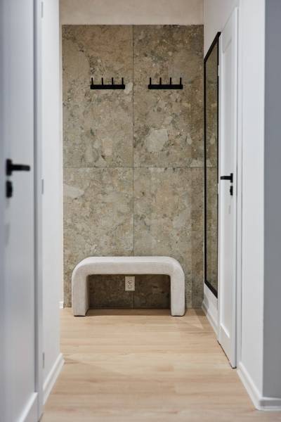 Előszoba padokkal, akasztókkal és fa dekorációjú padlóval egy kétszobás lakásban.