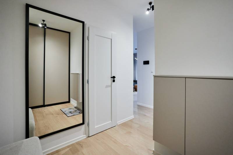 2 szobás lakás folyosója fa dekorációs padlóval és nagy tükörrel.