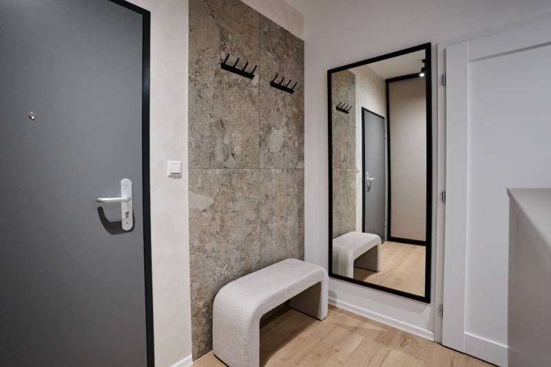 Előszoba egy kétszobás lakásban fogassal, tükörrel és fa dekorációjú padlóval.