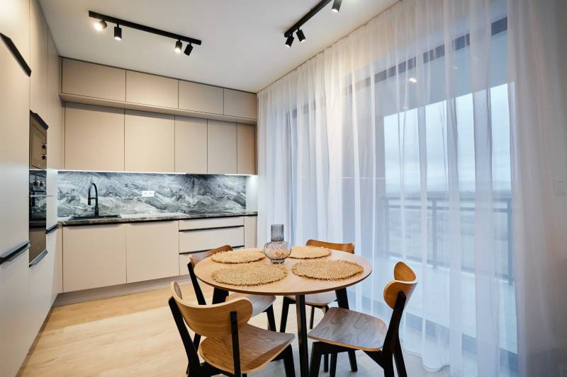 Konyha egy kétszobás lakásban fa dekor padlóval és étkezőasztallal.