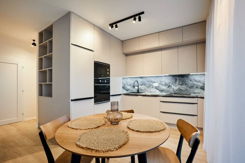 A kétszobás lakás konyhája kerek asztallal és fa mintázatú padlóval.