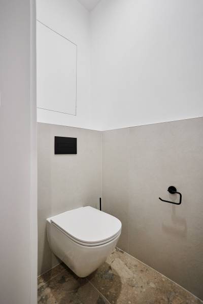 Fürdőszoba egy kétszobás lakásban minimalista dizájnnal és falra szerelt WC-vel.