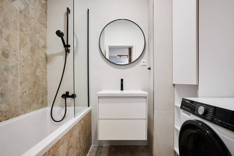 Fürdőszoba káddal, zuhanyzóval és mosógéppel egy kétszobás lakásban.