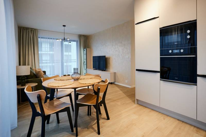 Nappali egy kétszobás lakásban, fa dekoros padlóval és étkezőasztallal.