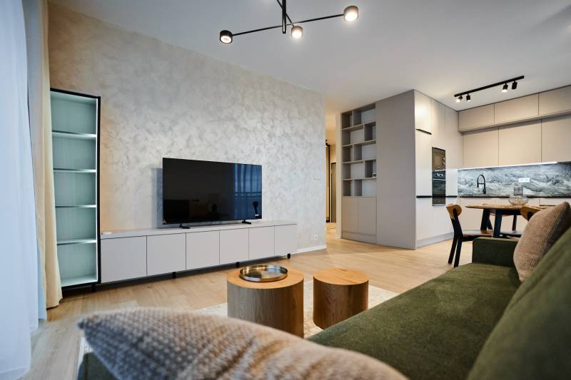 Nappali egy kétszobás lakásban fa dekor padlóval és modern konyhával.