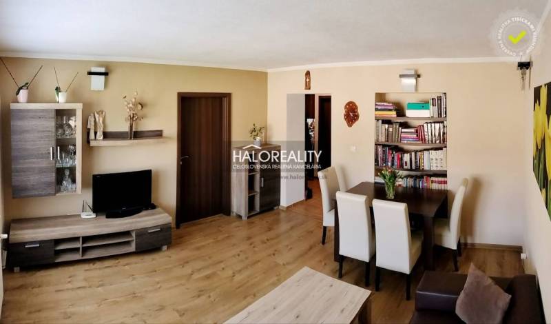 Nappali egy háromszobás lakásban fa dekor padlóval és étkező sarokkal.