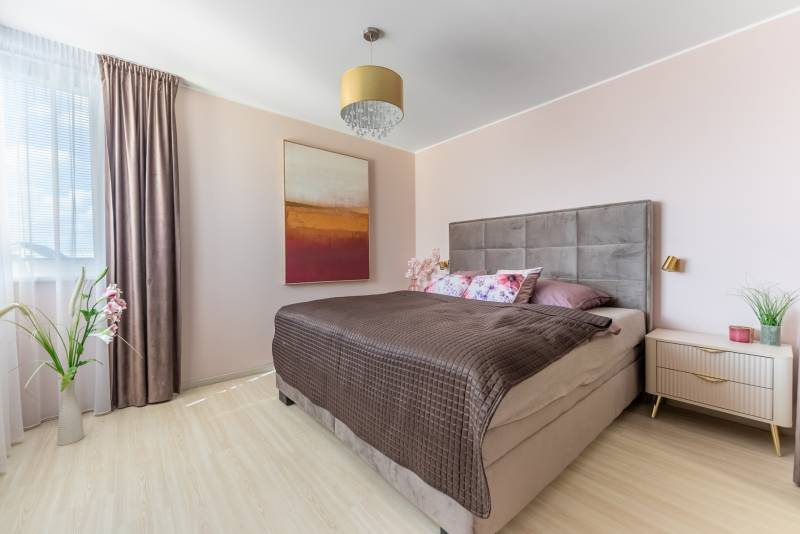 Hálószoba családi házban, ággyal, képpel, lámpával és fa dekorációjú padlóval.