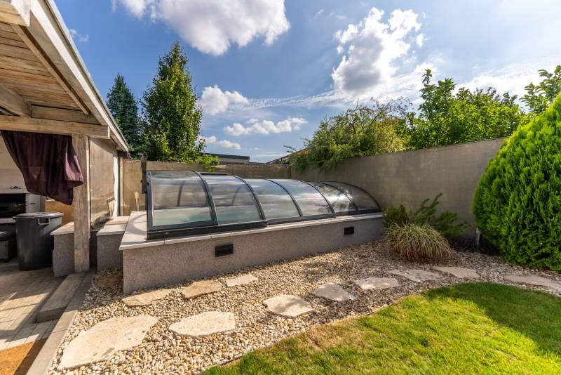 Családi ház kertje a Lovas utcában, Nagyszombatban, fedett medencével és zöldterülettel.