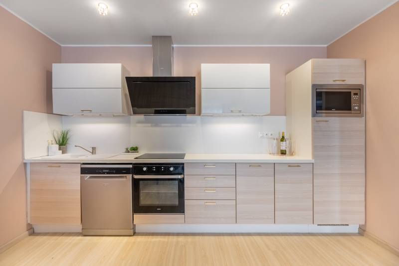 Konyha családi házban konyhabútorral, beépített készülékekkel és fa dekoros padlóval.