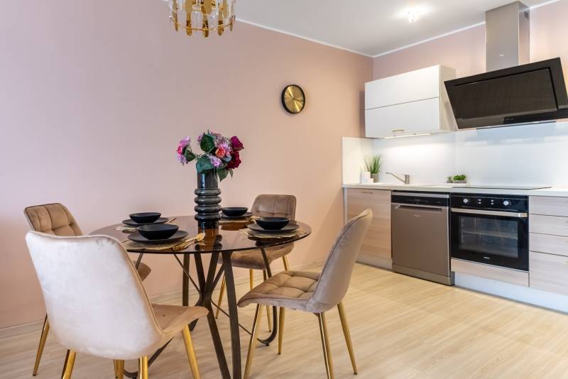 Ebédlő kerek asztallal és konyhapulttal egy családi házban, fa dekoros padlóval.