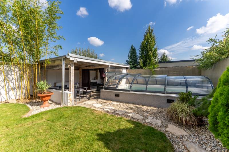 A Jazdecká utcai családi ház kertje Nagyszombatban, filagóriával és fedett medencével.