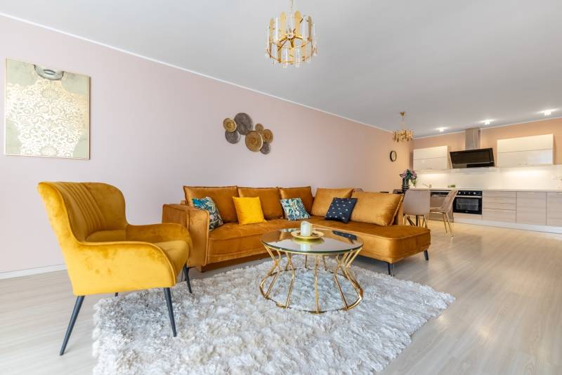 Nappali egy 4 szobás lakásban kényelmes kanapéval és fa dekorációjú padlóval.