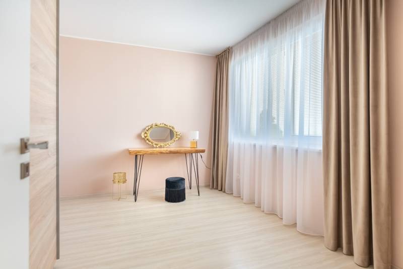 Világos szoba családi házban fésülködőasztallal, arany tükörrel és fa dekoros padlóval.