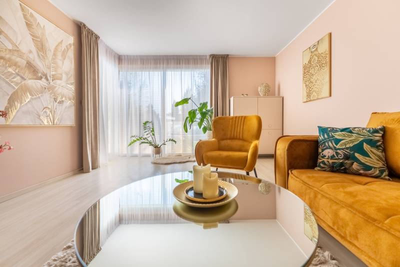 Családi ház nappalija kényelmes fotelekkel, dekoratív növényekkel és fa mintázatú padlóval.