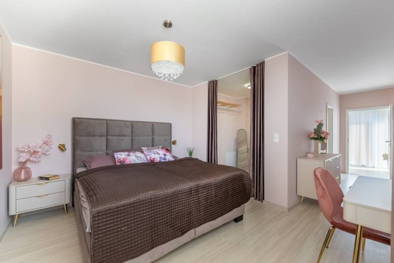 Hálószoba családi házban nagy ággyal, gardróbbal és fa dekorációjú padlóval.