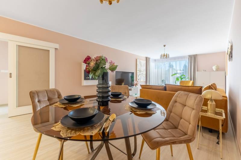 Egy étkezőasztal terítékkel, a háttérben egy családi ház nappalija.