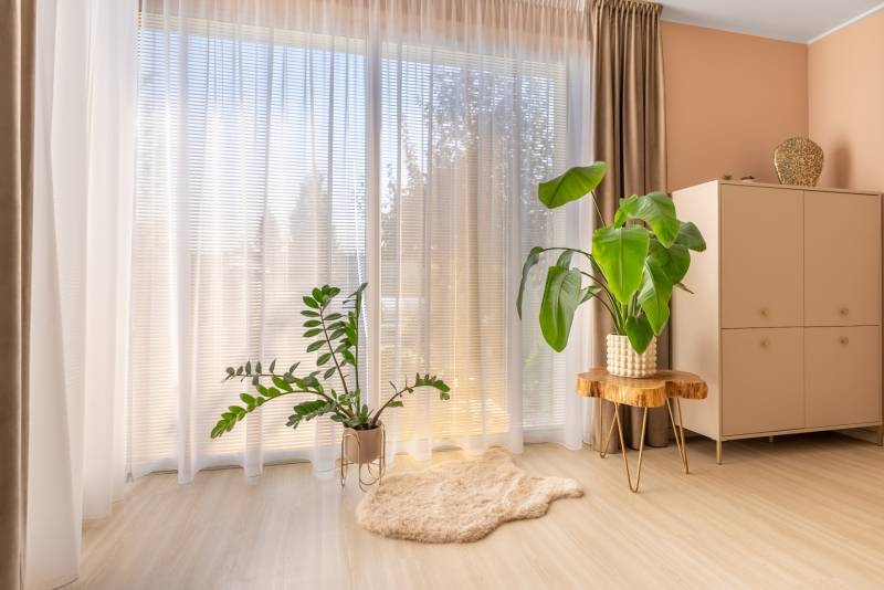 Egy családi házban van egy szoba fa dekorációjú padlóval, virágokkal és szekrénnyel.