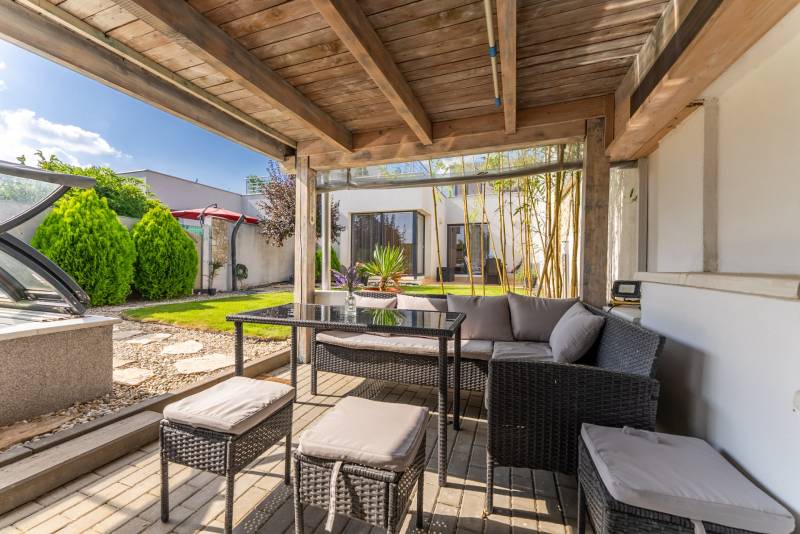 A Jazdecká utcai családi ház terasza Trnavában rattan bútorokkal és rejtett medencével.