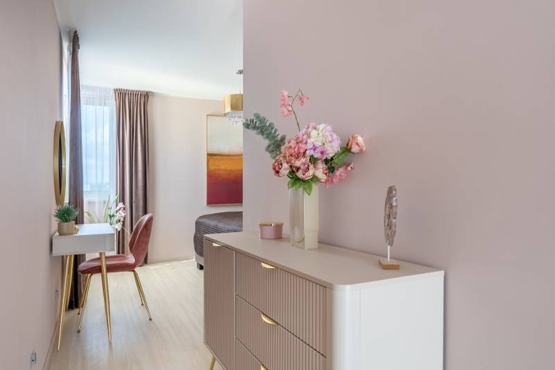 Virágdísz a komódon, tükör, szék és fa dekorációjú padló egy családi házban.