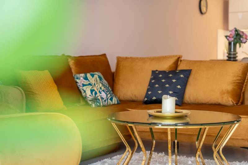 Családi ház kanapéval, asztallal gyertyával és díszpárnákkal.