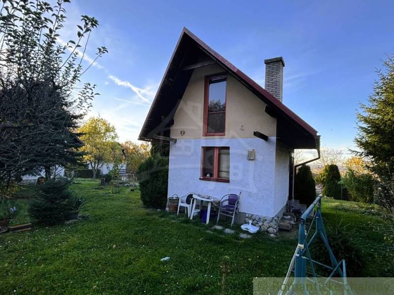 Ház Sološnicában rendezett kerttel, fákkal körülvéve és tiszta égbolttal.