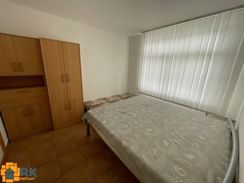 Hálószoba családi házban fehér rolókkal, ággyal és szekrényekkel.