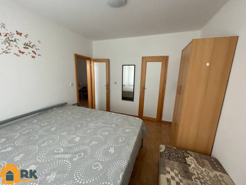 Hálószoba ággyal, szekrénnyel és tükörrel egy családi házban, fa dekoros padlóval.