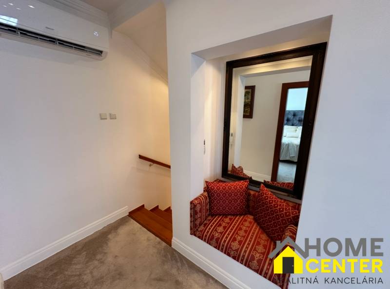 A családi ház lépcsőket mutat fa dekorral, tükröt és ülősarkot párnákkal.