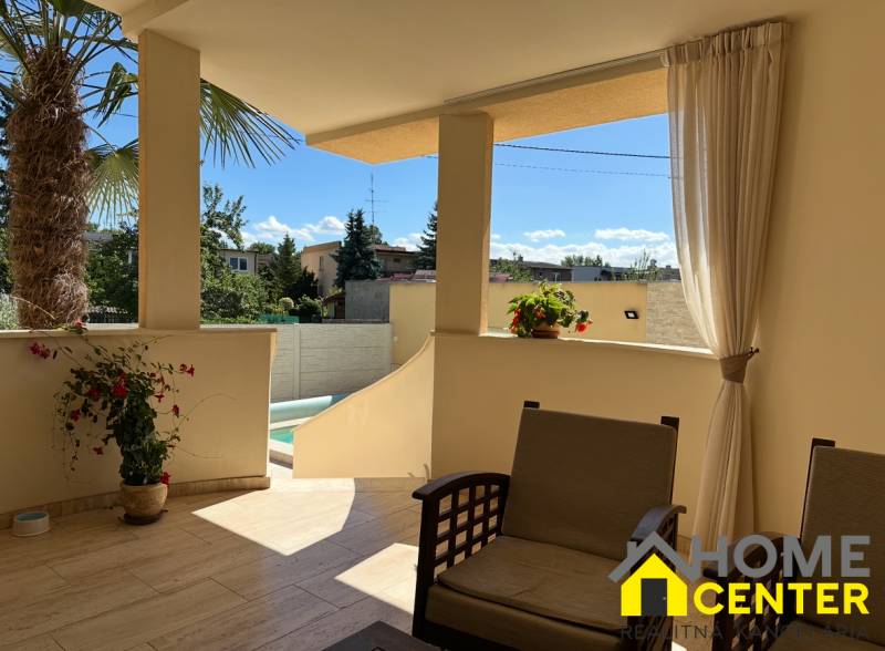 A komáromi családi ház terasza ülőhellyel és kilátással az udvarra, ahol pálmafa áll.