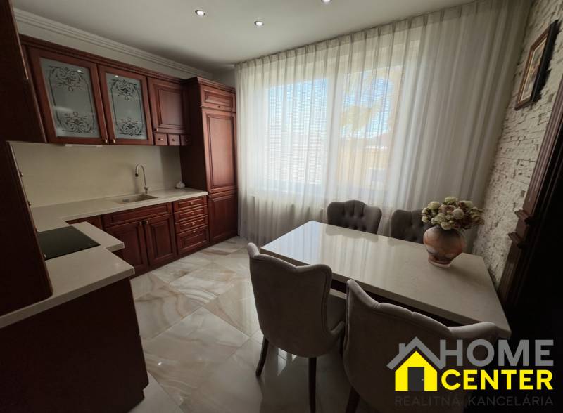 Konyha sötét szekrényekkel, fehér függönyökkel és virágos dekorációval egy családi házban.