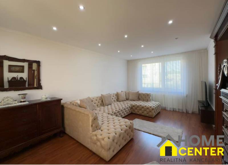 Nappali nagy kanapéval, fa dekoros padlóval és antik bútorokkal.