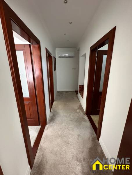 Egy családi ház folyosója fehér falakkal, szőnyeggel és fa ajtókeretekkel.