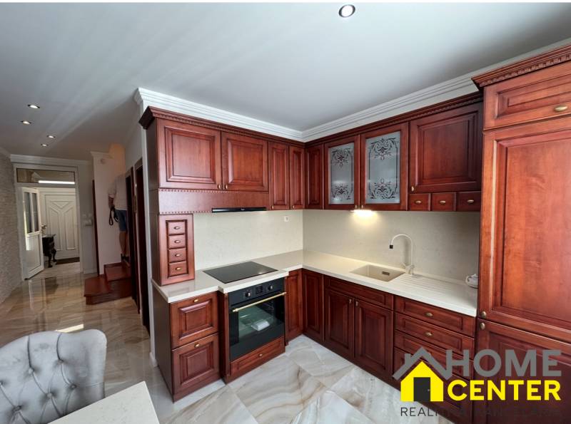 Konyha sötét fa szekrényekkel és fa dekorációjú padlóval egy családi házban.